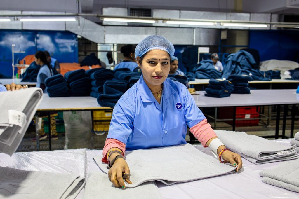 Image of a female textile worker folding fabrics in an industrial setting.