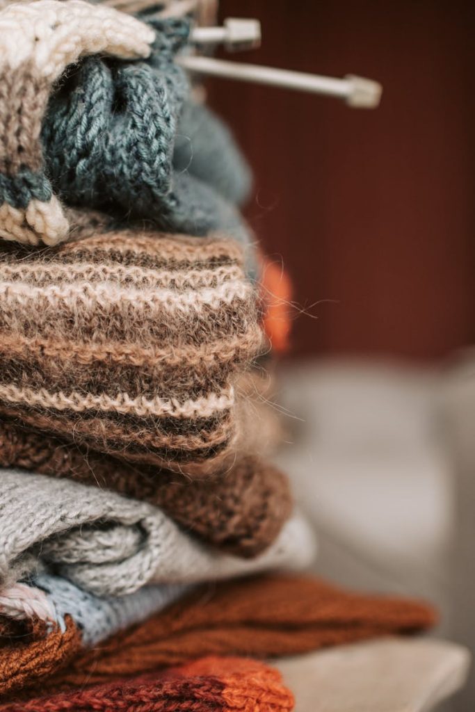 A stack of handmade knitted sweaters with knitting needles, exuding warmth and craftsmanship.